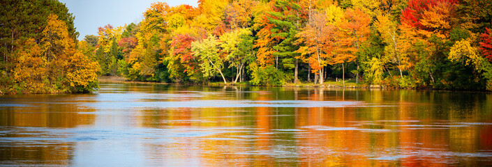 Colorful autumn trees reflecting off of the Wisconsin River in Merrill, Wisconsin - obrazy, fototapety, plakaty