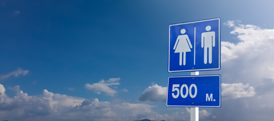 Traffic sign: toilet in 500 meters ahead sign on pole with clouds and bluesky background.