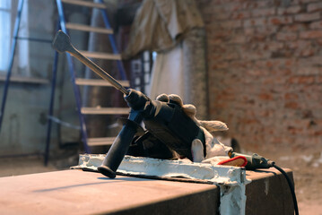 Hammer drill with chisel close up on the old brick wall background.
