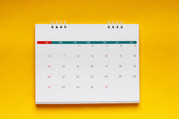 close up top view calendar schedule to make appointment meeting or manage timetable each day lay on yellow background for planning work and travel concept.