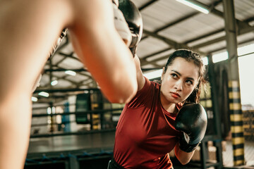 young woman boxer doing exercise hitting punching competing with her opponent at boxing camp