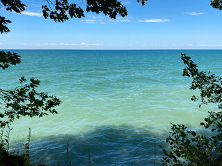 overlooking a green blue lake sea ocean river with overcast blue sky