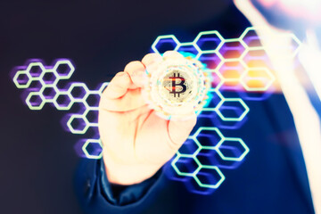 Businessman holds a gold bitcoin coin in his hands. Informational holographic panel with bright light effects. Virtual currency and blockchain concept.