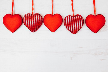 Red Valentine hearts hang with wooden clips on a natural string on a white door. Copy space. Concept of love