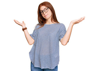 Young read head woman wearing casual clothes and glasses clueless and confused expression with arms...