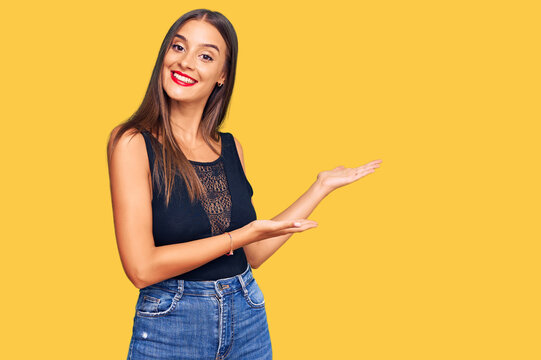 Young hispanic woman wearing casual clothes inviting to enter smiling natural with open hand
