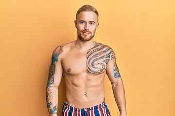 Fototapeta premium Young caucasian man wearing swimwear shirtless relaxed with serious expression on face. simple and natural looking at the camera.