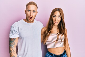 Young couple of girlfriend and boyfriend hugging and standing together in shock face, looking...