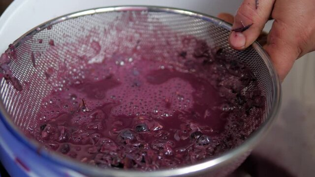 man filters grape must to make brandy