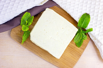 Top view of raw organic vegetarian tofu with fresh mint on wooden background.