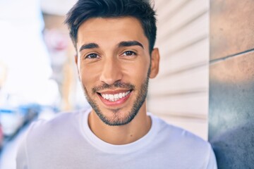 Young latin man smiling happy walking at the city.