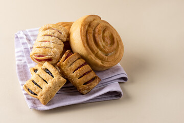 Variety of Homemade Puff Pastry Buns with Jam on Pink Napkin Yellow Background Copy Space
