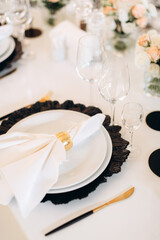 decoration of a wedding table, table setting for a wedding, white dishes on a wedding table with elements of gold leaves, themed decor