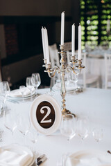 decoration of a wedding table, table setting for a wedding, white dishes on a wedding table with elements of gold leaves, themed decor