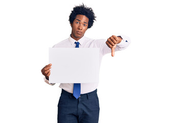 Handsome african american man with afro hair holding blank empty banner with angry face, negative...