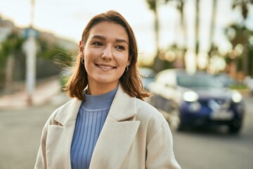 Young hispanic woman smiling happy standing at the city