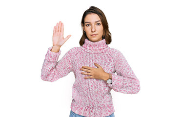 Young caucasian girl wearing wool winter sweater swearing with hand on chest and open palm, making...