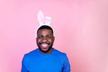 happy young brazil man with bunny ears in studio pink wall background