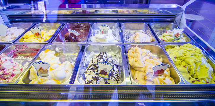 ice cream shop with many delicious flavors on display, chocolate, pistachio, cream, hazelnut, milk, fruit, candied fruit