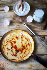 Frying pan with pancake, flour, milk, eggs. Pancake making concept. Maslenitsa celebration.