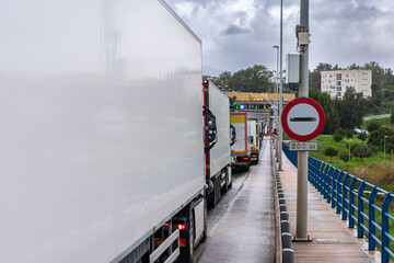 Customs or next border sign next to a line of trucks waiting to cross.