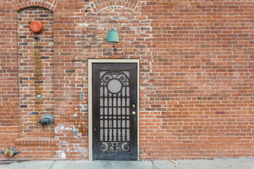 Obraz premium Decorative metal door on red brick building on overcast day in rural New Mexico