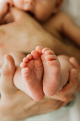 Close-up of the newborn's leg in the hands of the dad.