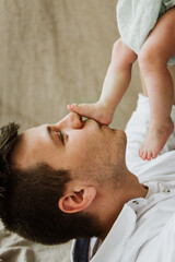 Fototapeta na wymiar Young dad kisses the feet of a newborn close-up.