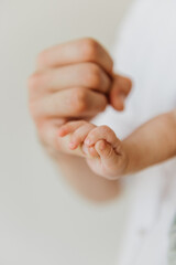Handle of a newborn close-up in the hands of dad. Newborn baby holds dad's finger in close-up.
