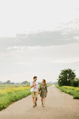 Young parents hug and kiss their newborn daughter in nature.