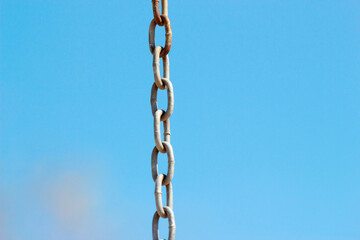 Fototapeta premium Metal chain from a swing in park on a background of blue day sky