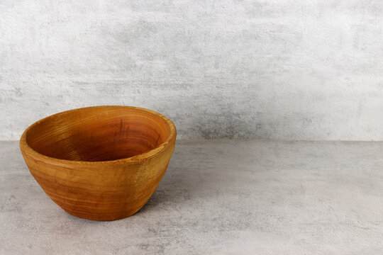 Rustic Wooden Bowl Made Of One Piece Of Wood On Gray Table And Wall.