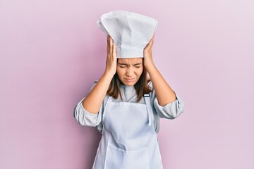 Young beautiful woman wearing professional cook uniform and hat suffering from headache desperate and stressed because pain and migraine. hands on head.