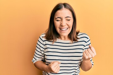 Obraz premium Young beautiful woman wearing casual striped t shirt celebrating surprised and amazed for success with arms raised and eyes closed