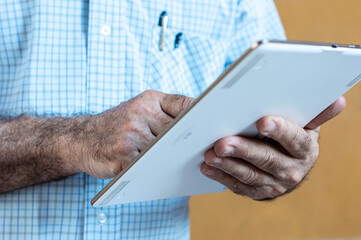 Man hands holding a tablet with a yellow background