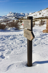 Mountain routes signpost in snowy landscape. Vertical format.