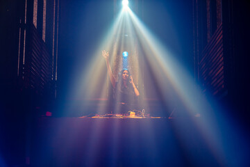 DJ on stage in disco night club mixing techno music beat . Nightlife and dance party .