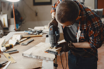 Wood cutting with circular saw. Closeup of mature man sawing lumber.