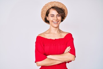 Young hispanic woman wearing summer hat happy face smiling with crossed arms looking at the camera. positive person.