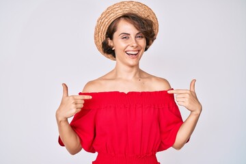 Young hispanic woman wearing summer hat looking confident with smile on face, pointing oneself with fingers proud and happy.