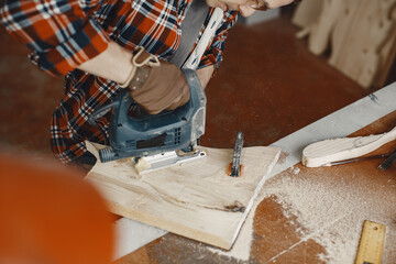 Wood cutting with circular saw. Closeup of mature man sawing lumber.