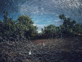 The drought theme image The cracked glass is in the shape of a spider web with trees sky and park...