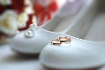 a pair of gold rings on the bride's white shoes. details of the preparation for the wedding