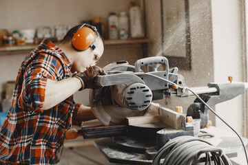 Wood cutting with circular saw. Closeup of mature man sawing lumber.