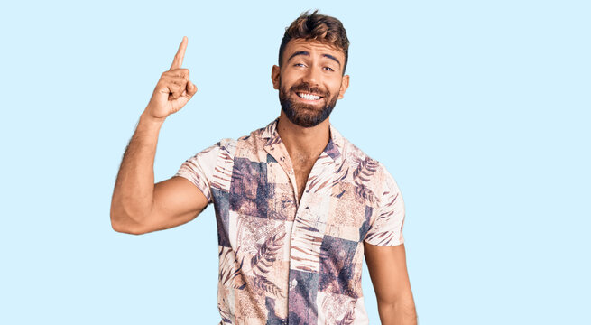 Young hispanic man wearing summer clothes pointing finger up with successful idea. exited and happy. number one.