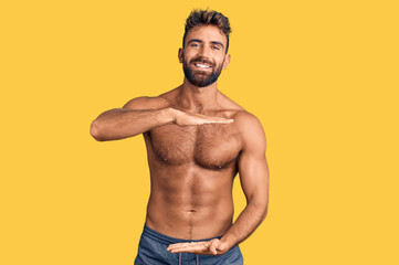 Young hispanic man wearing swimwear shirtless gesturing with hands showing big and large size sign,...