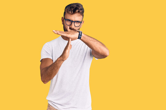 Young hispanic man wearing casual clothes and glasses doing time out gesture with hands, frustrated and serious face
