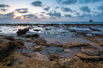 Rocky coastline with shipwreck at sunset time