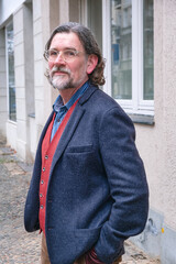 handsome man in his 50s standing in front of building