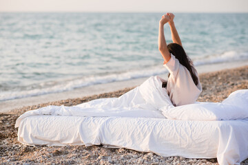 Fototapeta na wymiar Woman wearing pajamas wake up in bed at beach over nature sea background closeup. Good morning. Summer season. Freedom concept.